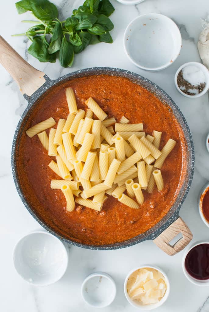 Cooked rigatoni added to pasta sauce.