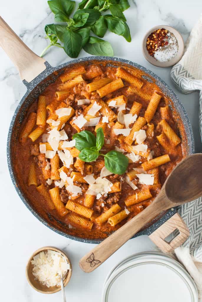 Rigatoni pasta with cheese sauce topped with cheese and basil.