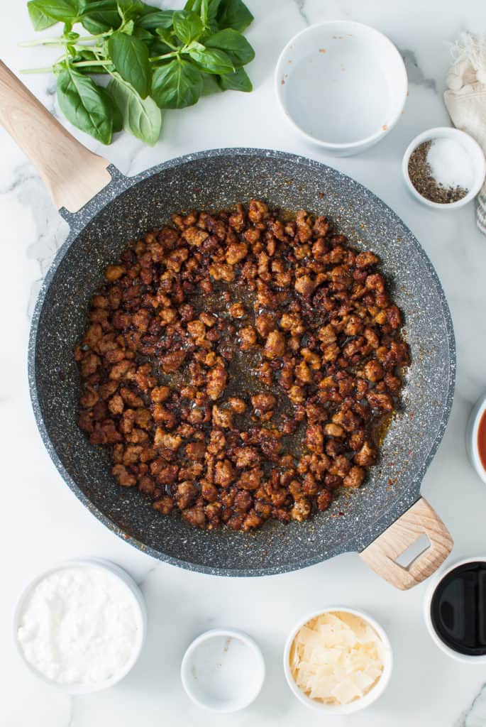 Italian sausage and seasonings cooked in a pan.