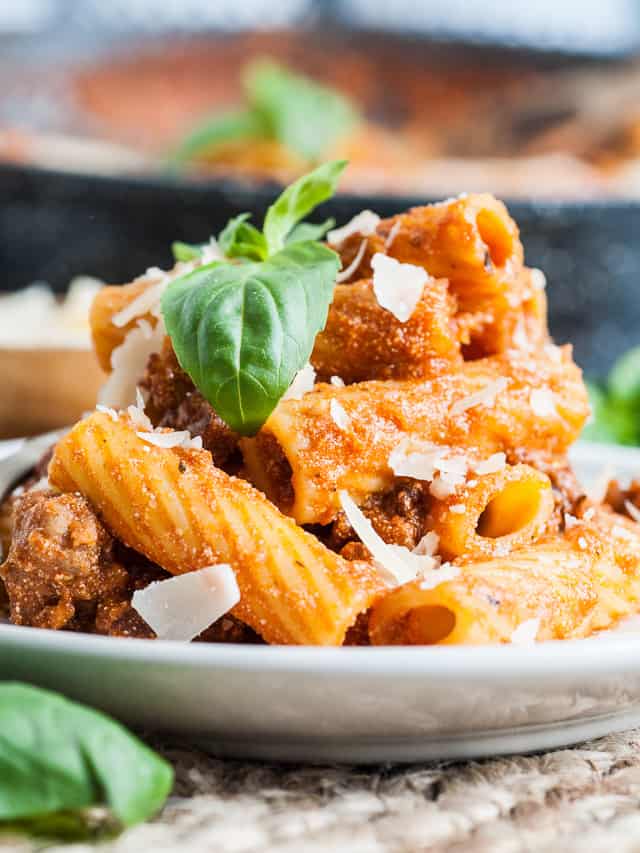 White serving dish piled high with italian sausage pasta.