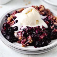 Close up view of berry crisp on a plate with ice cream.