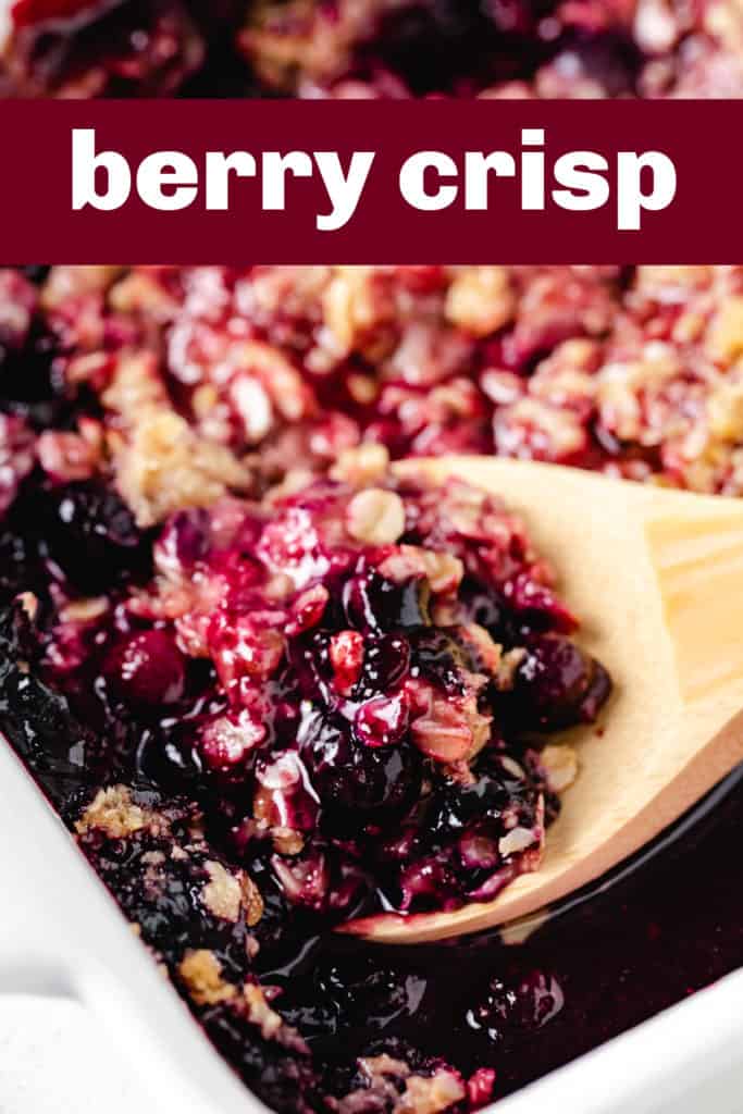 Spoon scooping freshly baked berry crisp from a pan.