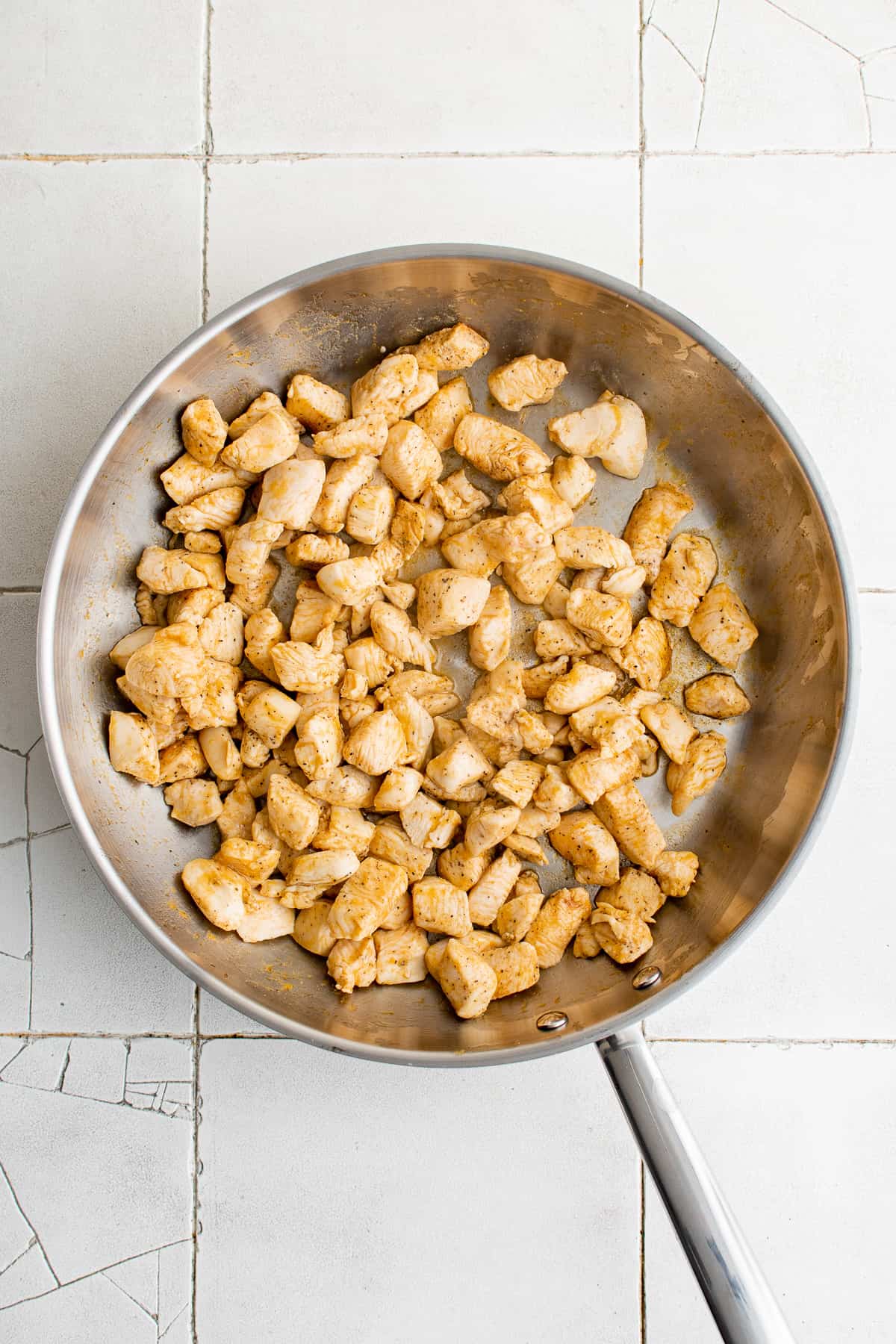 Seasoned diced chicken in a skillet.