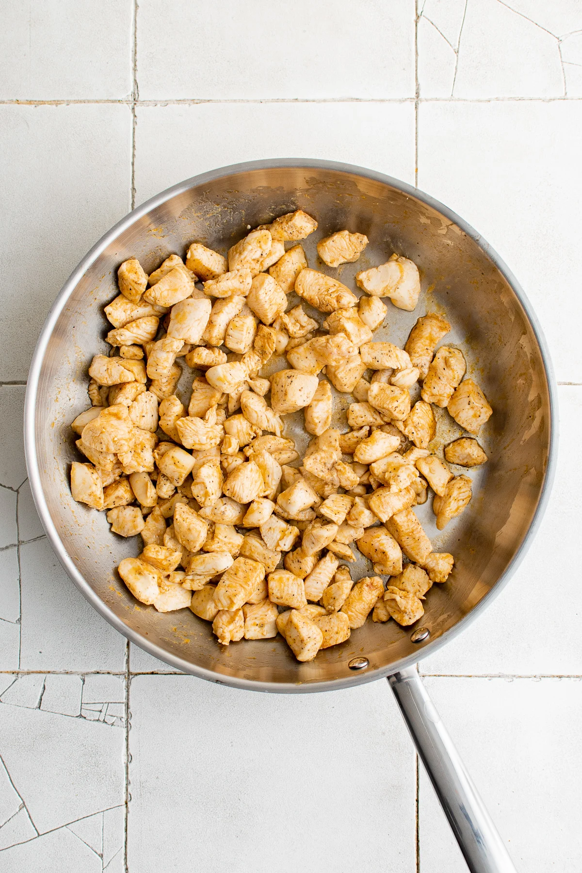 Seasoned diced chicken in a skillet.