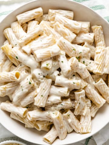 Close up view of a dish of rigatoni noodles cover in cream cheese sauce.