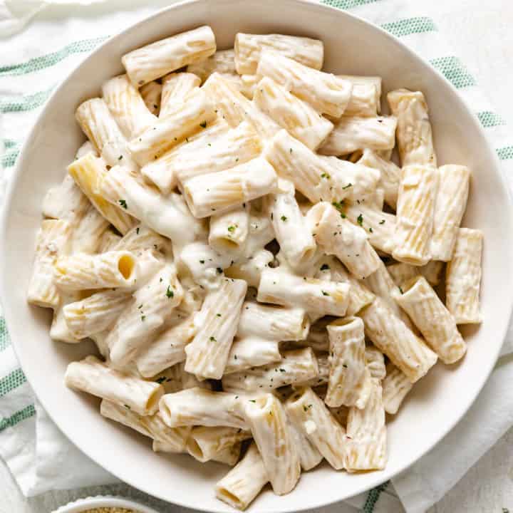 Close up view of a dish of rigatoni noodles cover in cream cheese sauce.