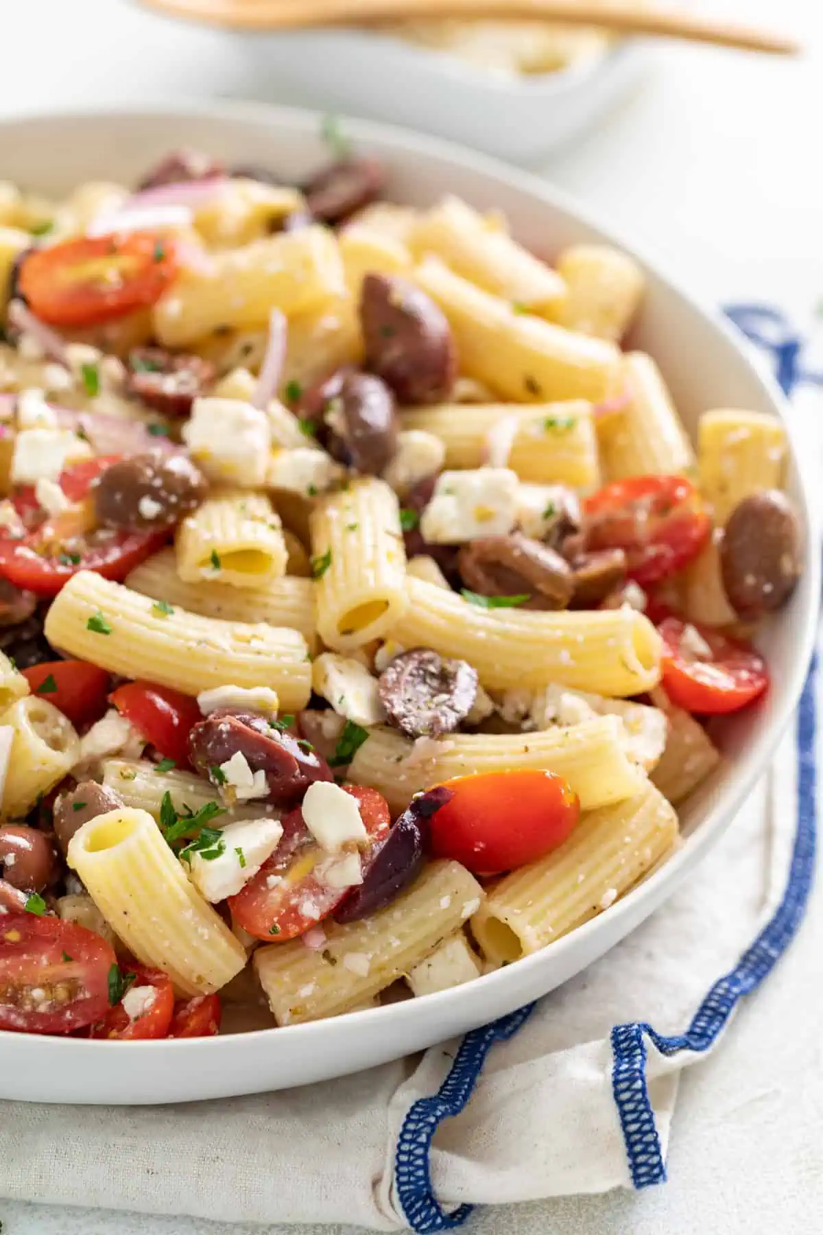 Olives, tomatoes, and feta in pasta salad in a dish.