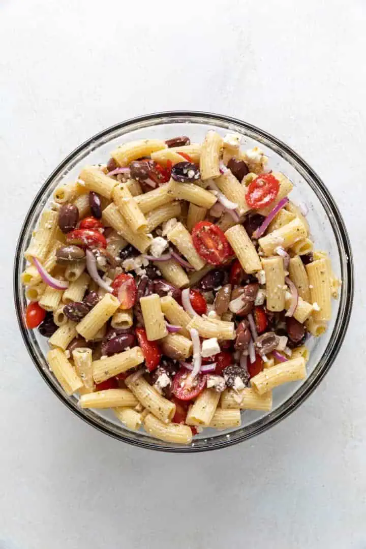 Pasta salad mixed in a glass bowl.