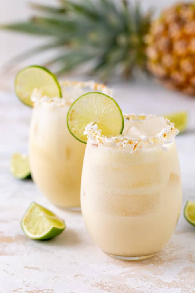Two tropical pineapple and coconut margaritas on ice.