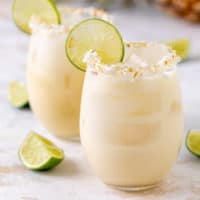 Side view of two glasses of tropical margaritas with limes.