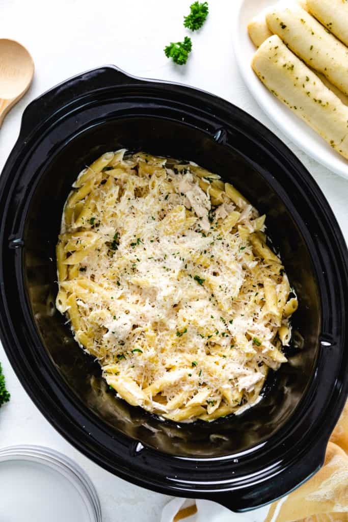 Top down view of a crockpot filled with parmesan chicken pasta.