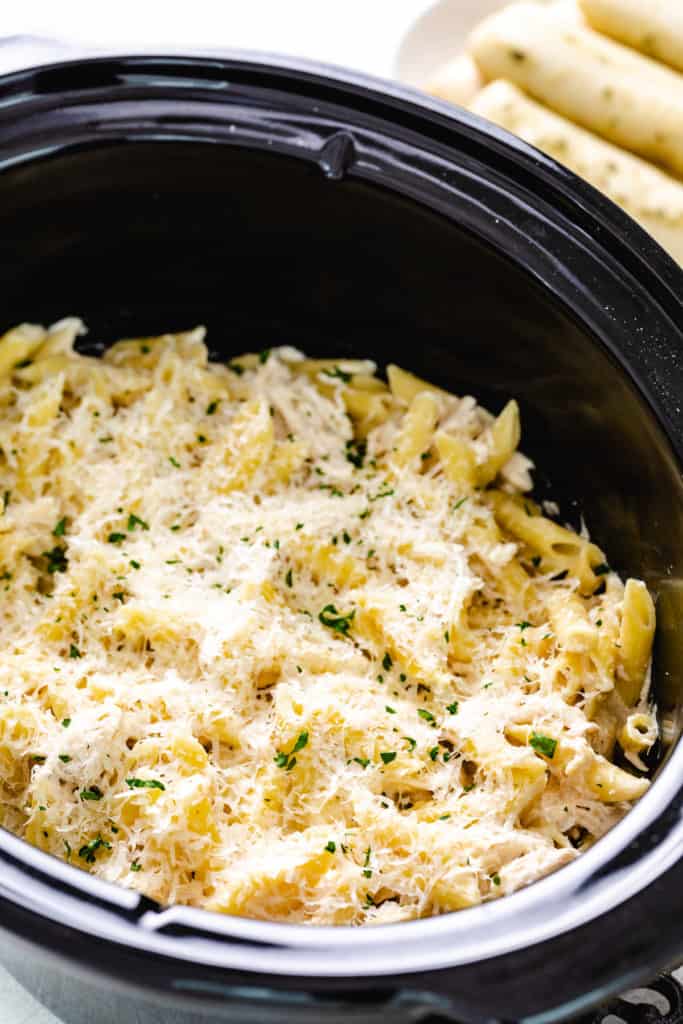 Close up view of parmesan cheese on top of chicken pasta.