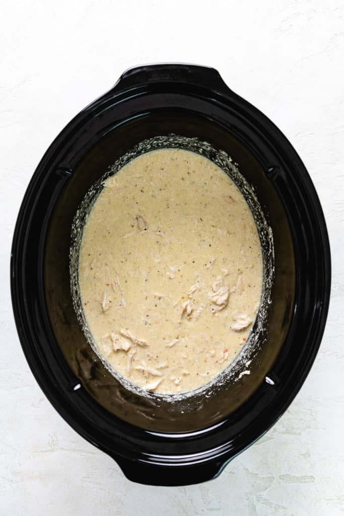 Shredded chicken, cream cheese, and Italian dressing in a crockpot.