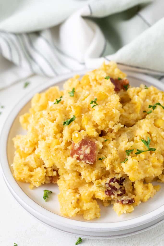 Scoop of corn casserole on a stack of plates.