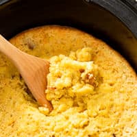 Wooden spoon scooping homemade corn casserole.