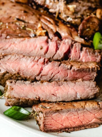 Close up view of sliced sirloin steak on a plate.