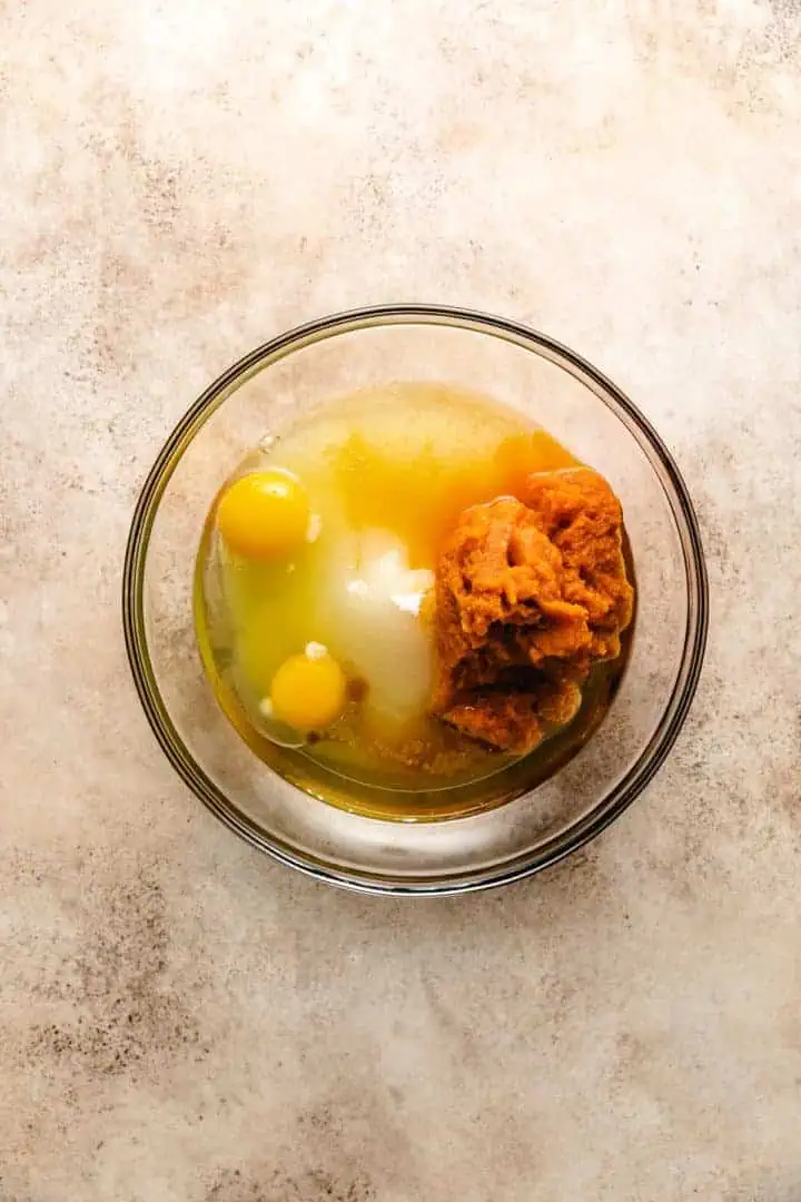 Eggs, pumpkin, sugar and oil in a bowl.