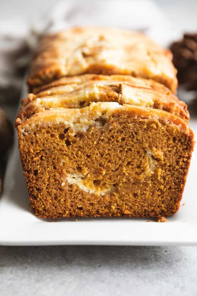 Side view of a loaf of pumpkin cream cheese bread.