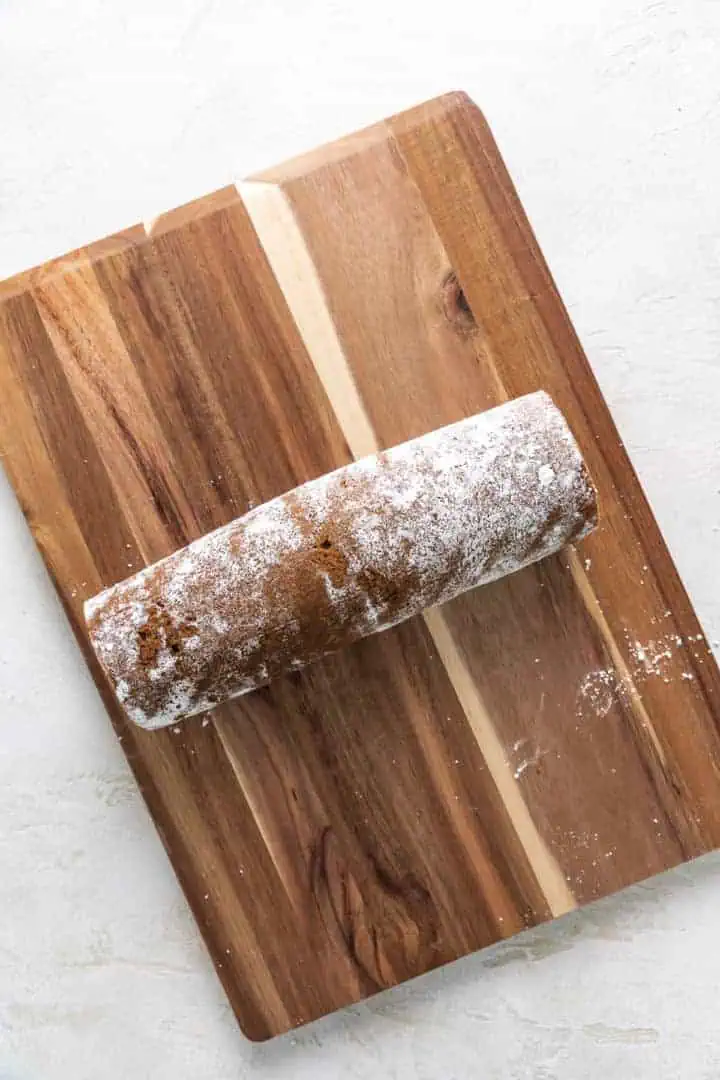 Pumpkin roll placed on a cutting board.