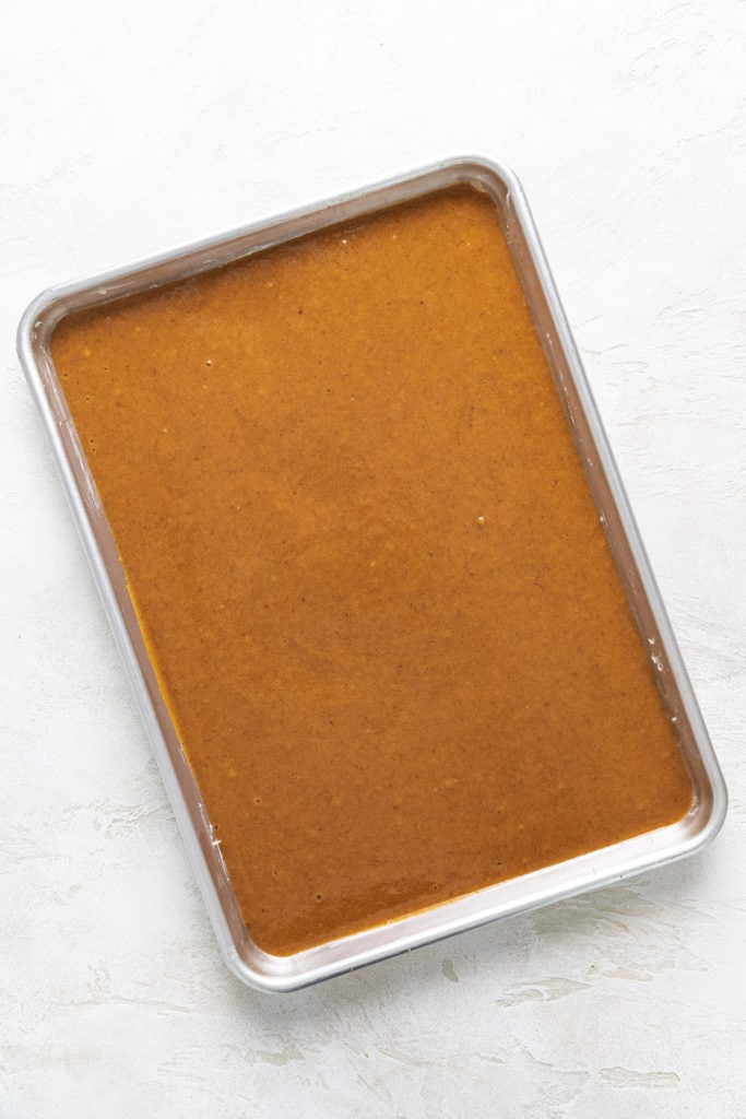 Pumpkin cake batter poured into a jelly roll pan.