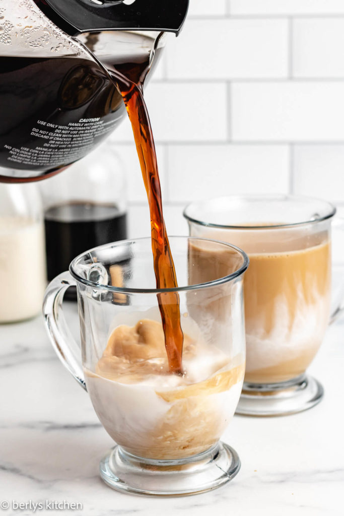 Coffee being poured into a glass coffee mug.