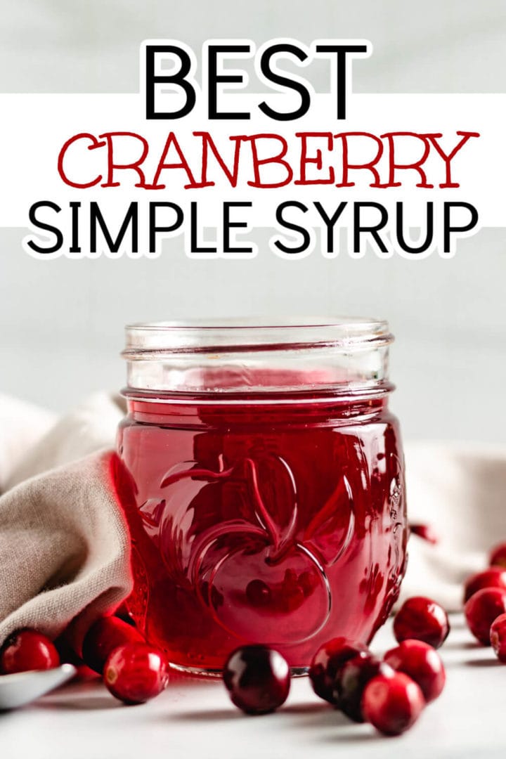 Cranberries in front of a jar of simple syrup.