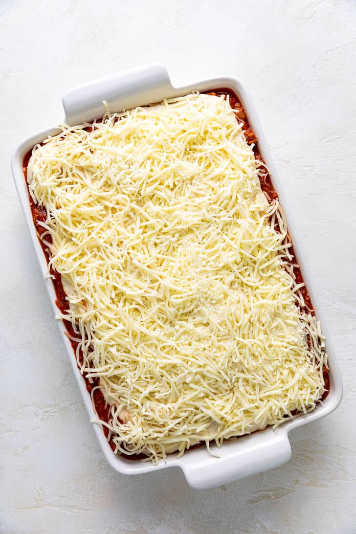 Shredded mozzarella sprinkled over a pan of pasta.