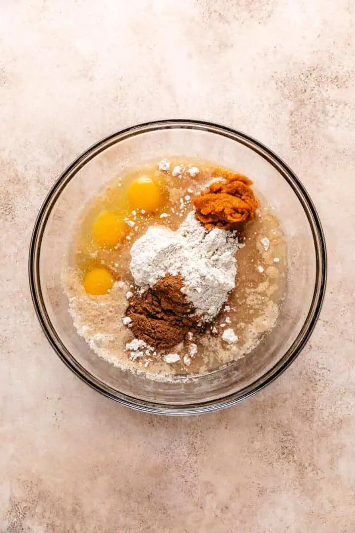 Cake mix, oil, eggs, water, and pumpkin pie spice in a mixing bowl.