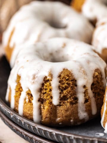 Close up view of mini pumpkin bundt cakes on a stack of plates.