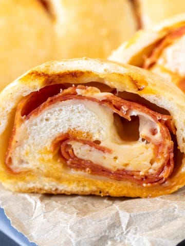 Close up view of a sliced pepperoni roll on parchment.