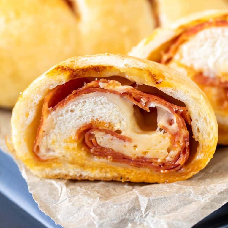 Close up view of a sliced pepperoni roll on parchment.