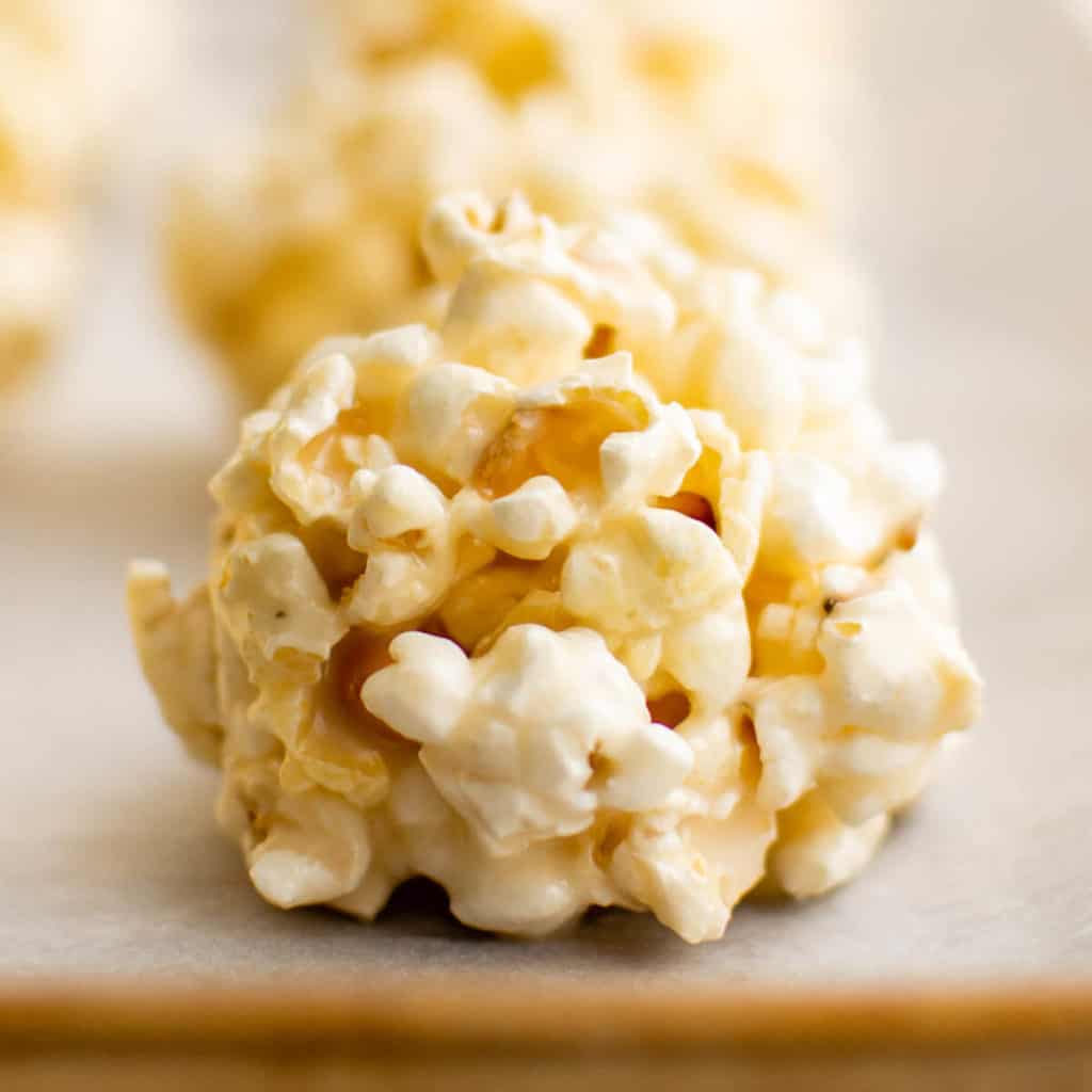 Close up view of a popcorn ball on parchment paper.