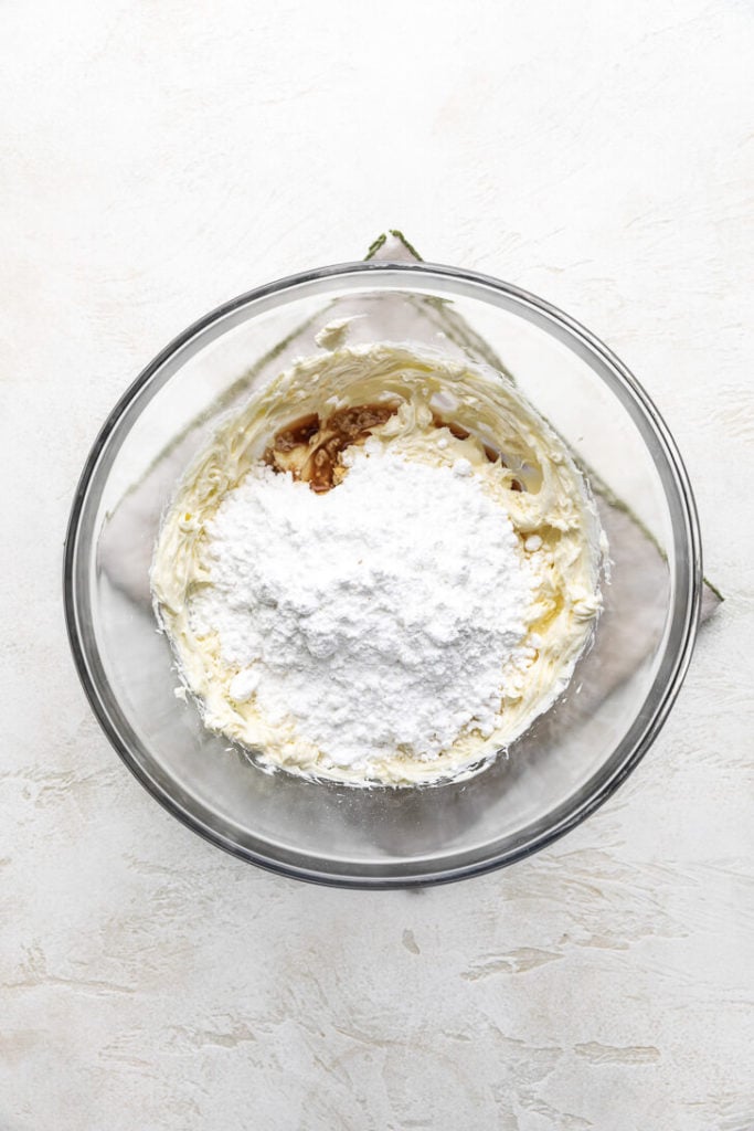 Powdered sugar and vanilla added to a bowl of cream cheese and butter.