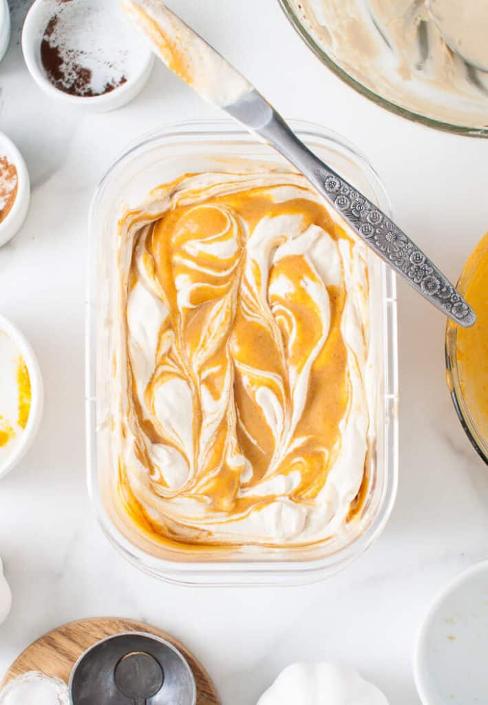 Ice cream and pumpkin mixture swirled together with a knife.