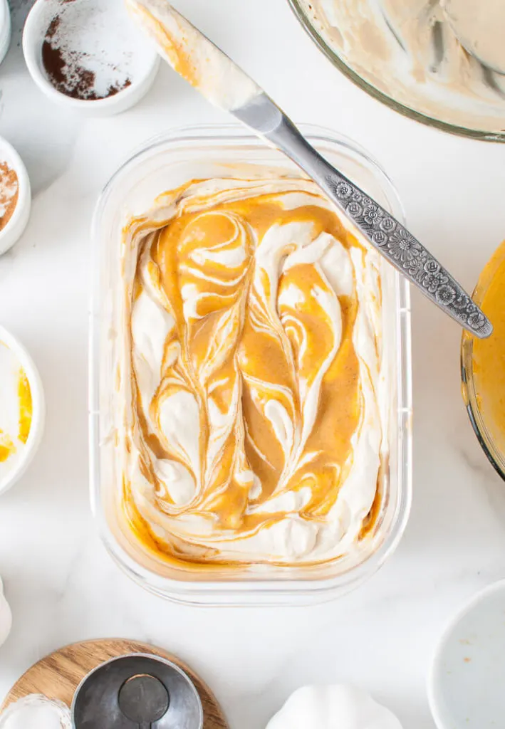 Ice cream and pumpkin mixture swirled together with a knife.