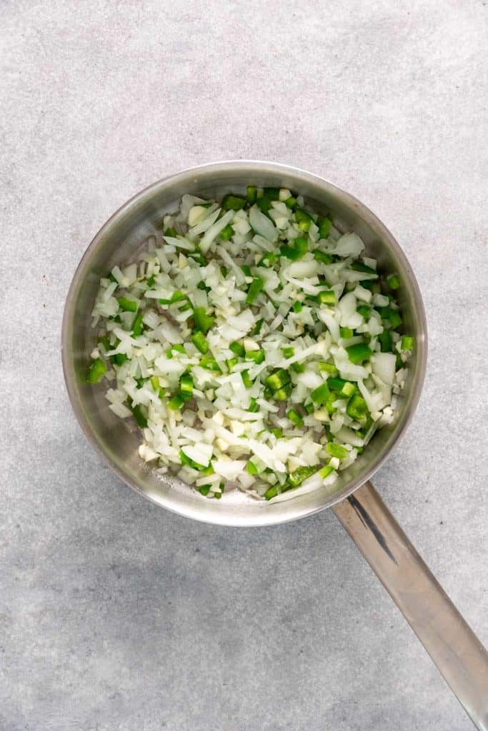 Jalapeños and onions cooking in a skillet.