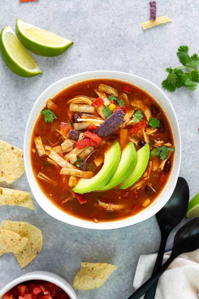 Top down view of a bowl of soup next to two spoons.