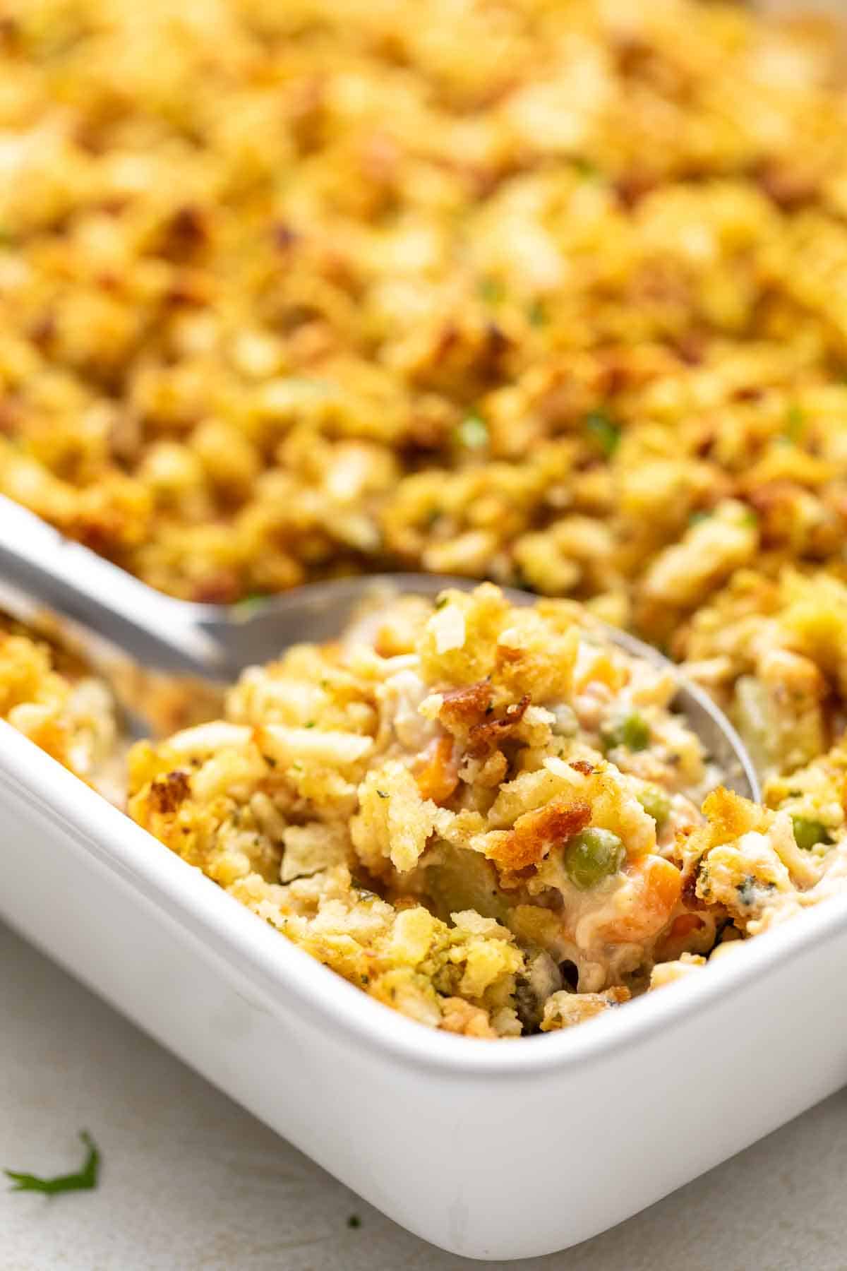 Close up view of a spoon scooping casserole from a pan.