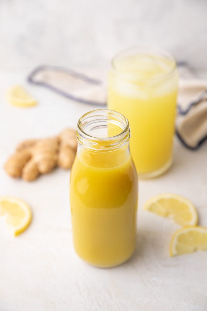 Jar of ginger simple syrup next to a lemon slice.