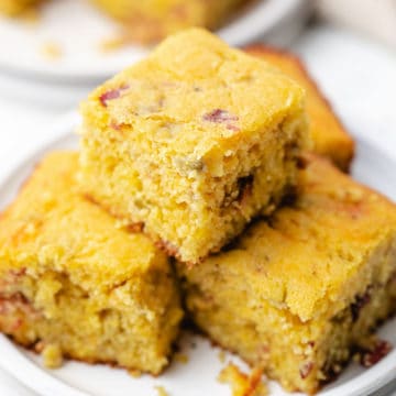 Close up view of several pieces of cornbread on a white dish.