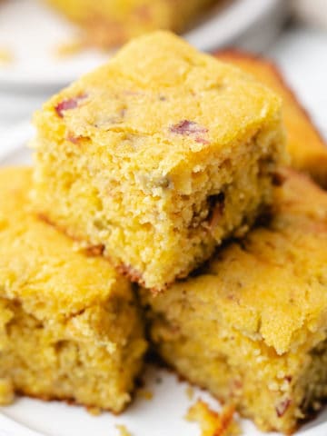 Close up view of several pieces of cornbread on a white dish.