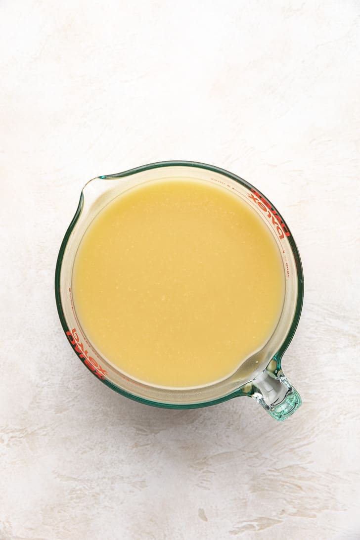 Broth, water, and chicken whisked together in a measuring cup.