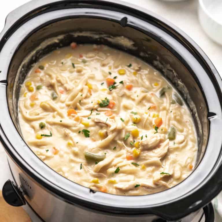 Close up view of chicken, noodles and vegetables in a slow cooker.