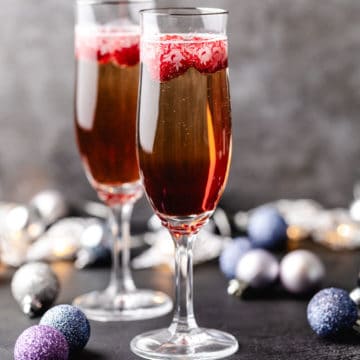 Side view of two glasses of champagne with raspberry liqueur.