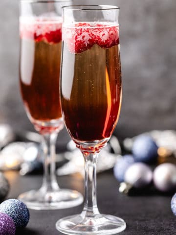 Side view of two glasses of champagne with raspberry liqueur.