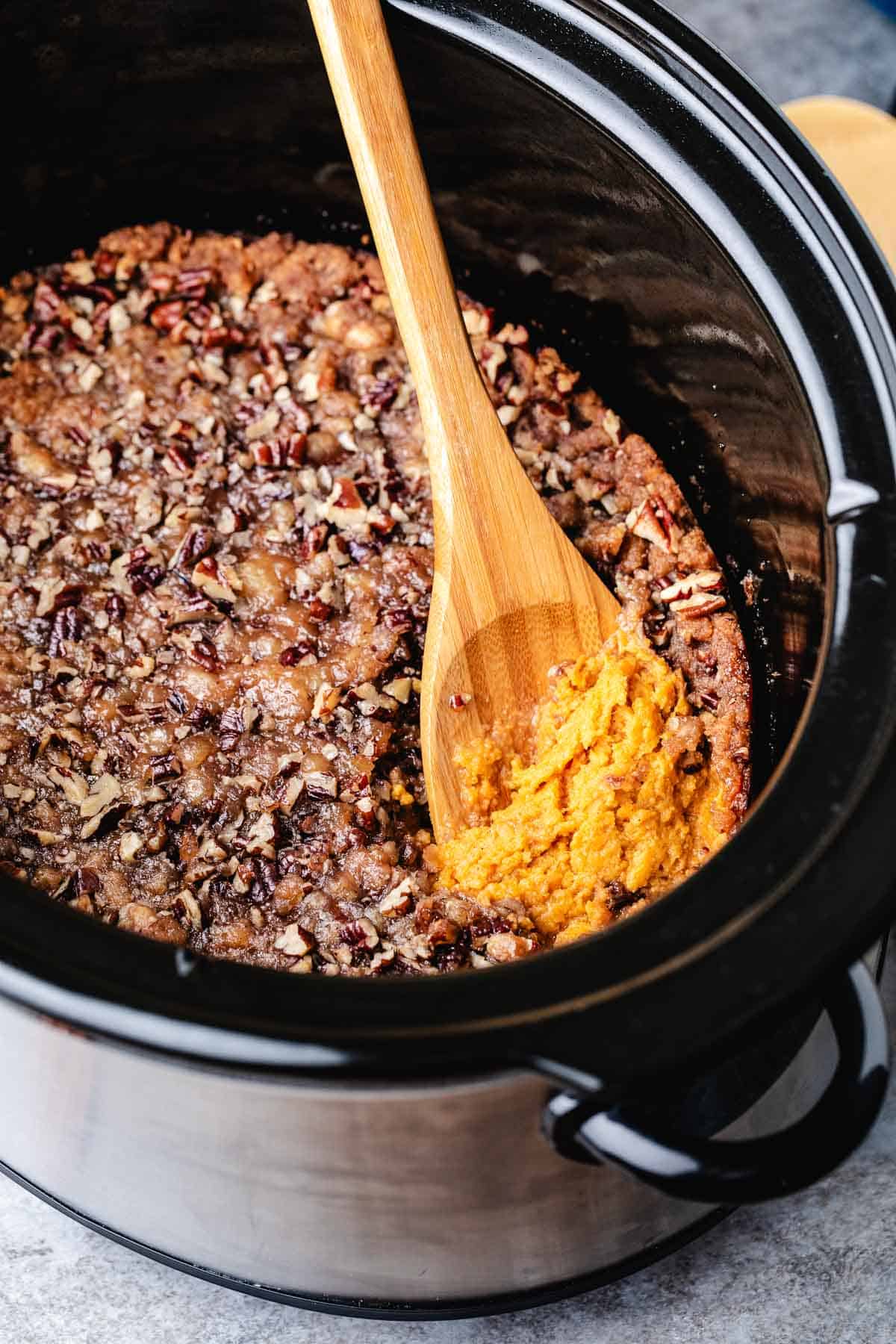 Spoon scooping sweet potato casserole from a slow cooker.