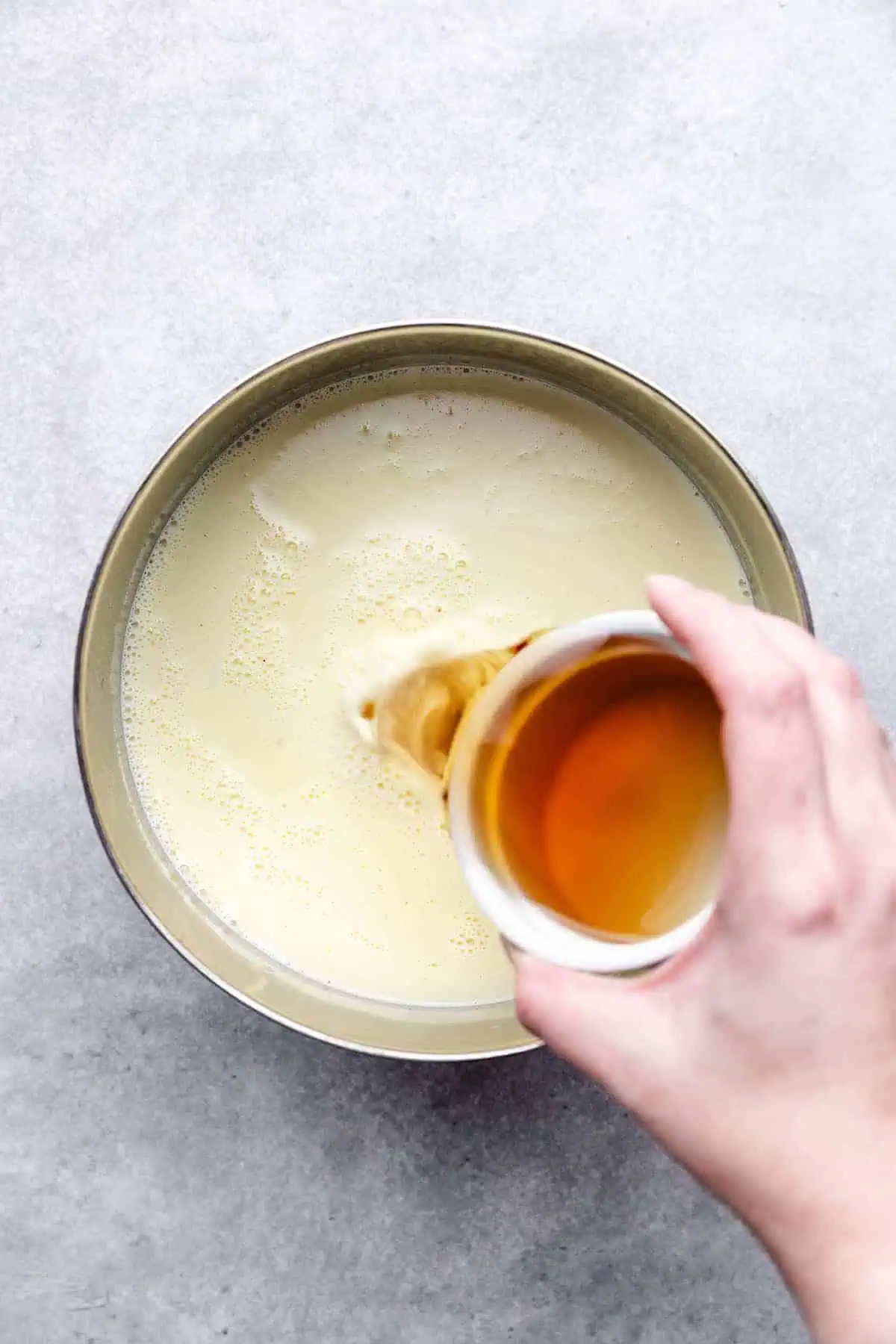 Top down view of bourbon being poured into a pan of eggnog.