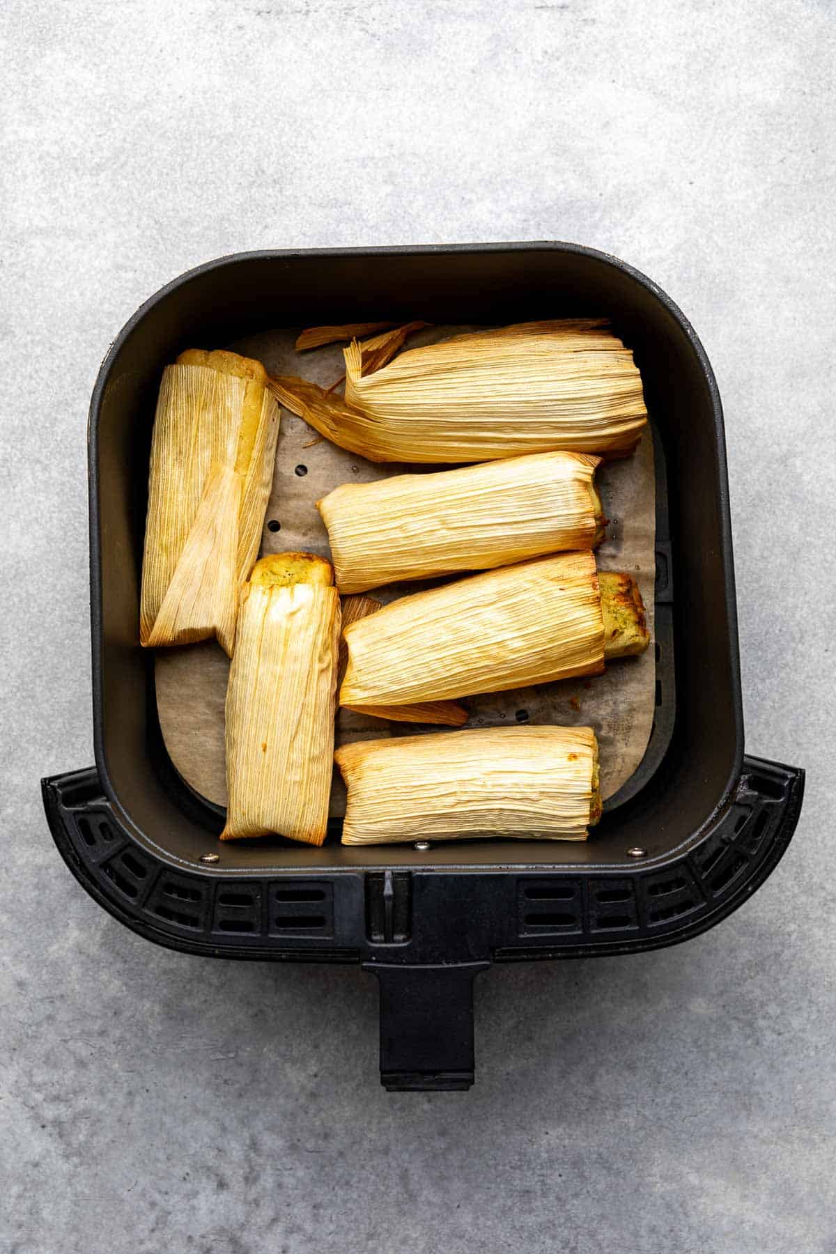 Tamales arranged in an air fryer basket.