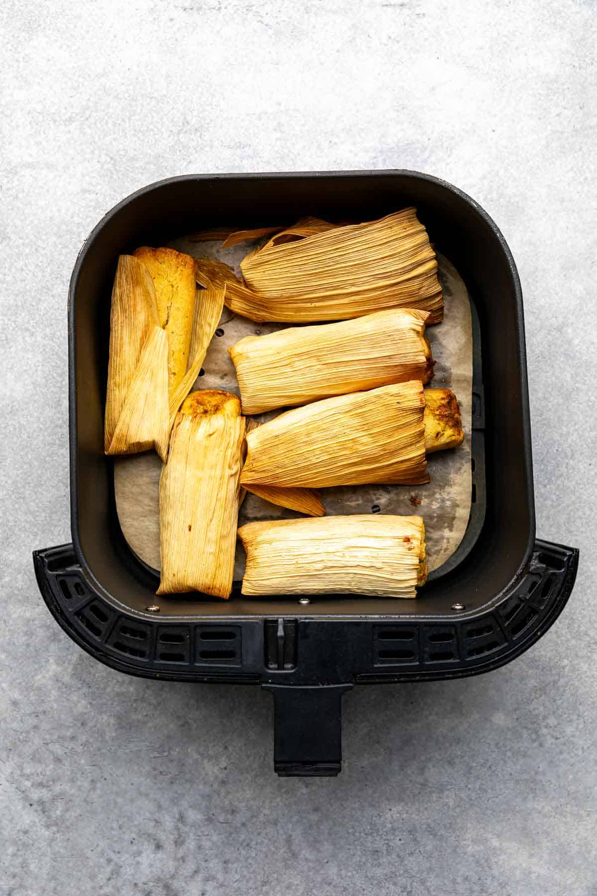 Cooked tamales in an air fryer basket.