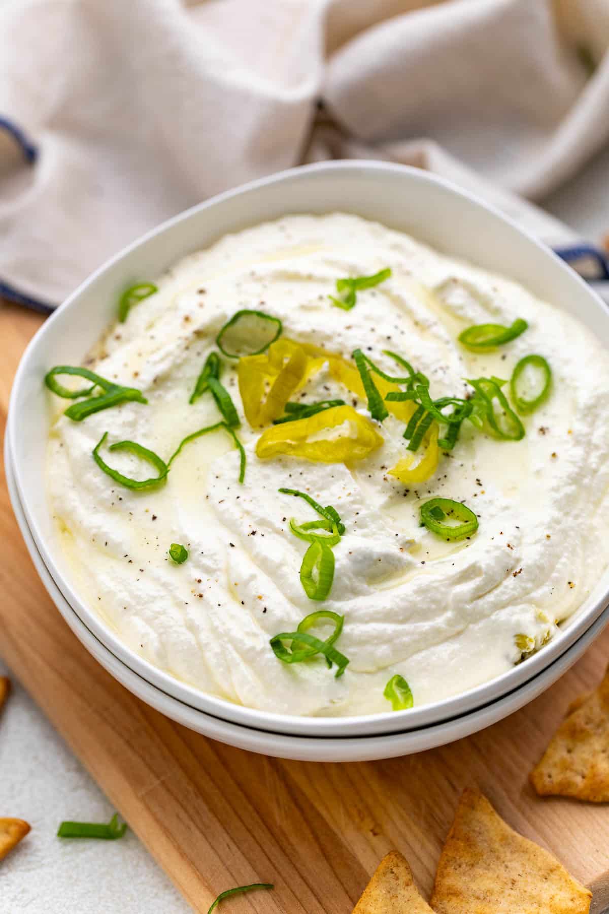 Cream cheese dip with pepperoncini in a white bowl.